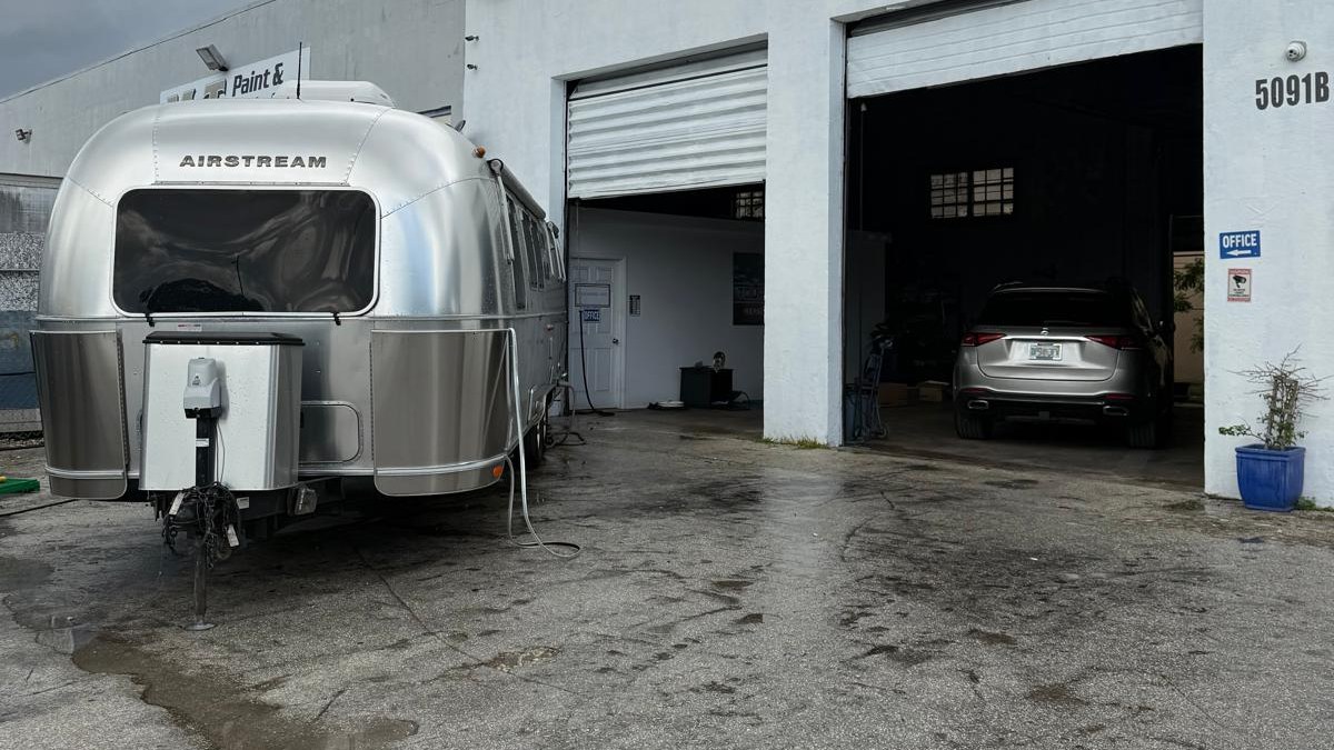 An Airstream travel trailer outside the open repair bays at Tour America RV's in Doral
