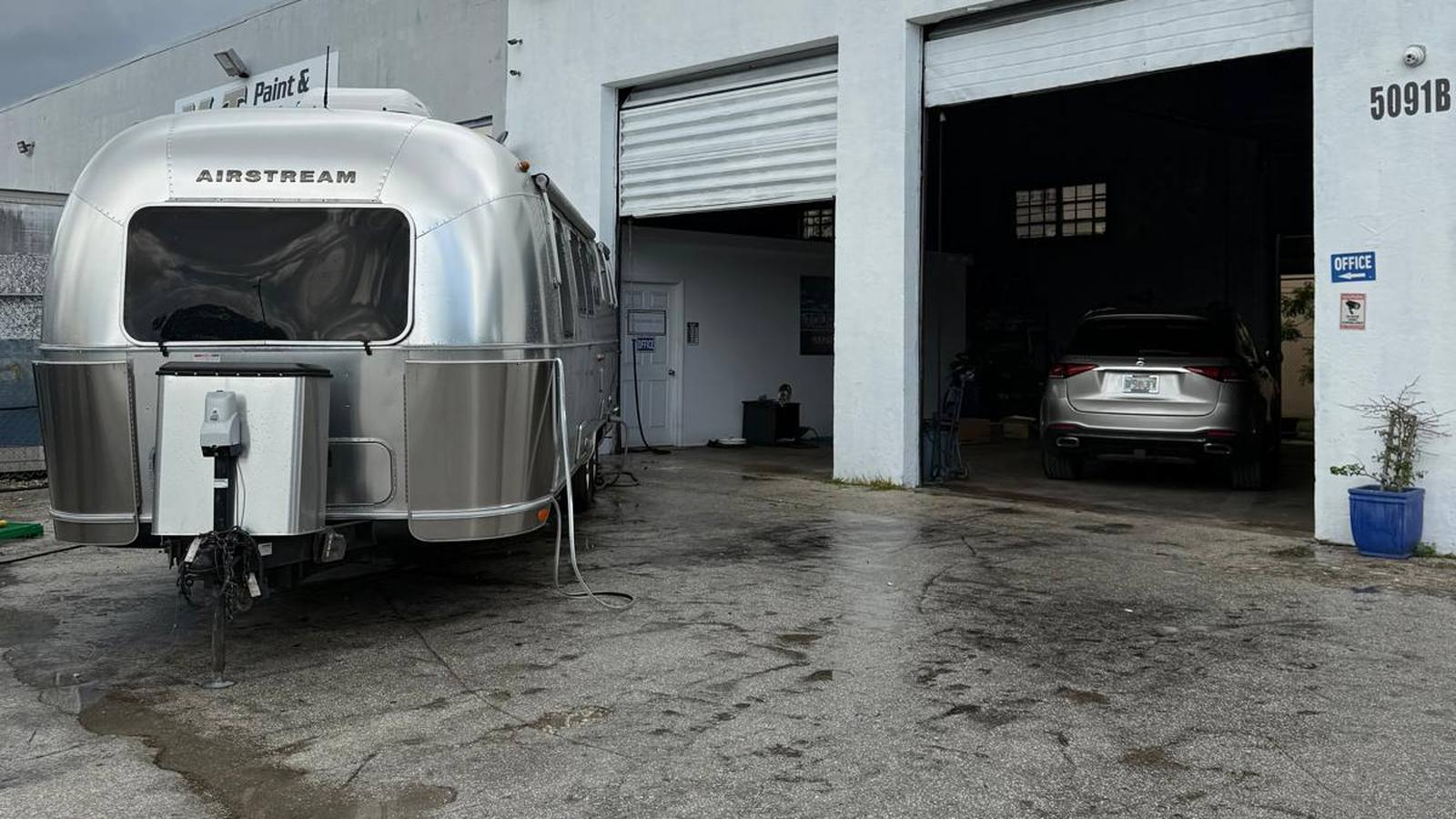 An Airstream travel trailer outside the open repair bays at Tour America RV's in Doral